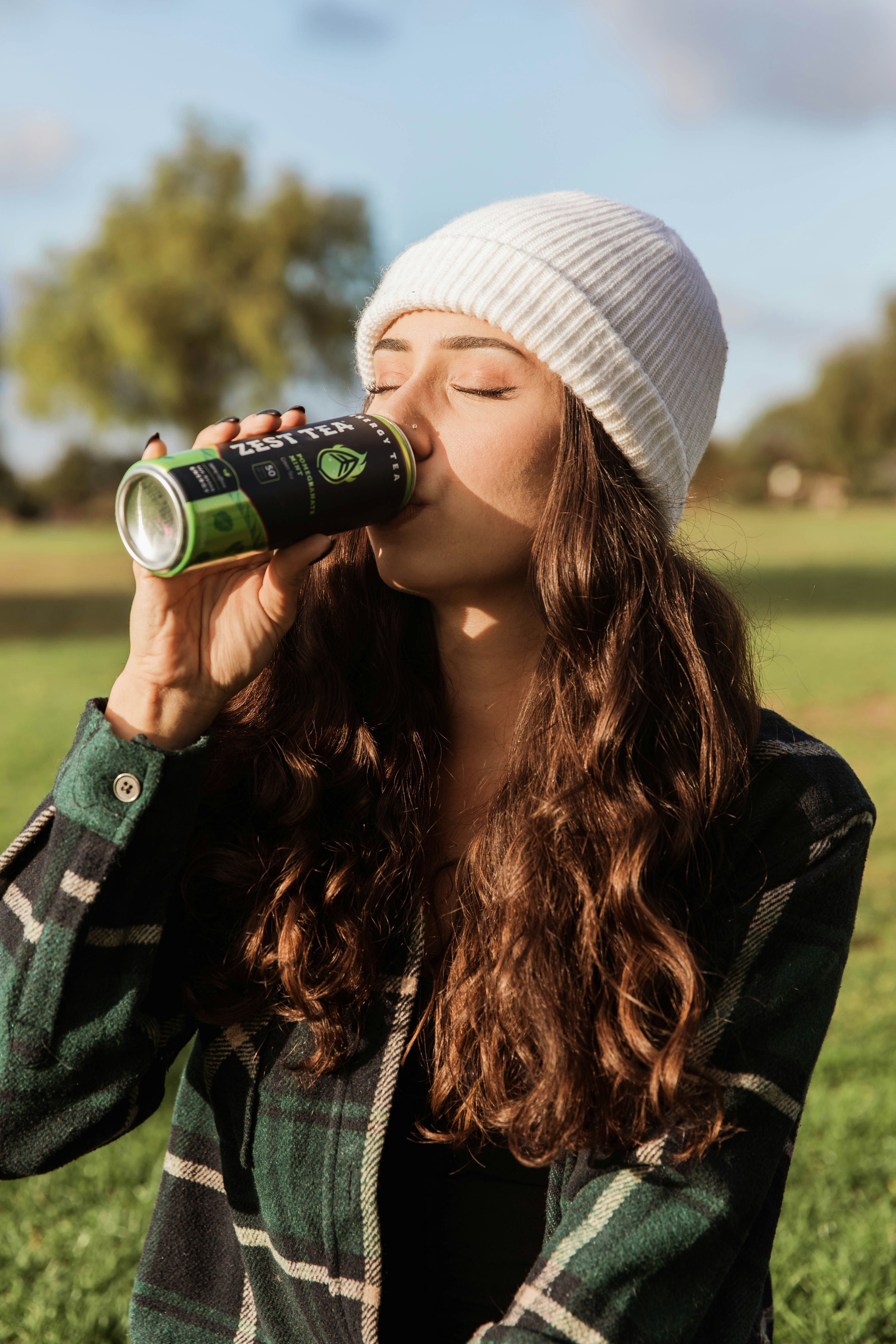 woman in green and black camouflage jacket drinking on green can